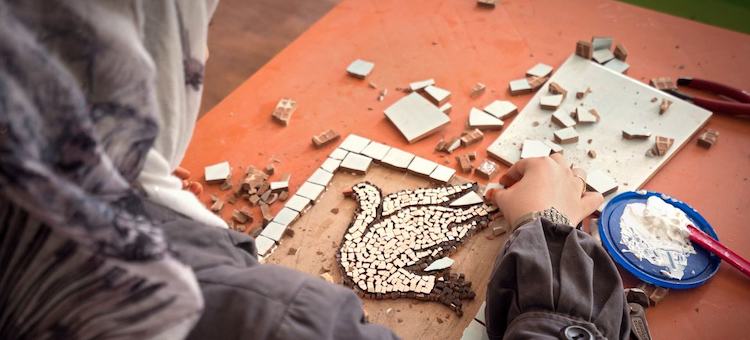 Photo: A woman crafts a mosaic depicting a peace dove in the Za’atari refugee camp in Jordan. © UN Women/Christopher Herwig